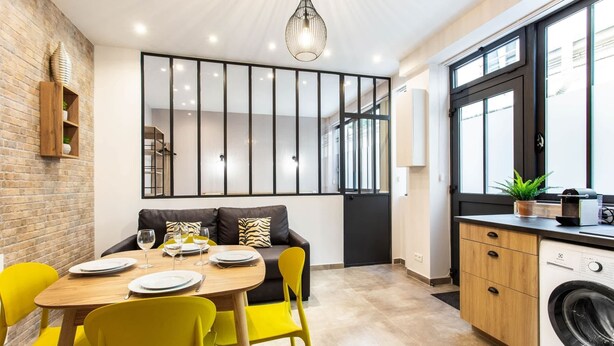 A modern kitchen with a dining area, a washing machine, and a large window.