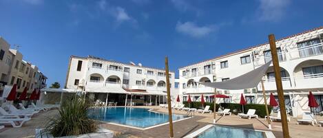 Ein Poolbereich mit mehreren Pools, Liegestühlen und Sonnenschirmen.