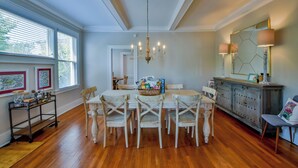 Un coin repas comprenant une table en bois, six chaises, un lustre et un buffet avec un miroir et des lampes.