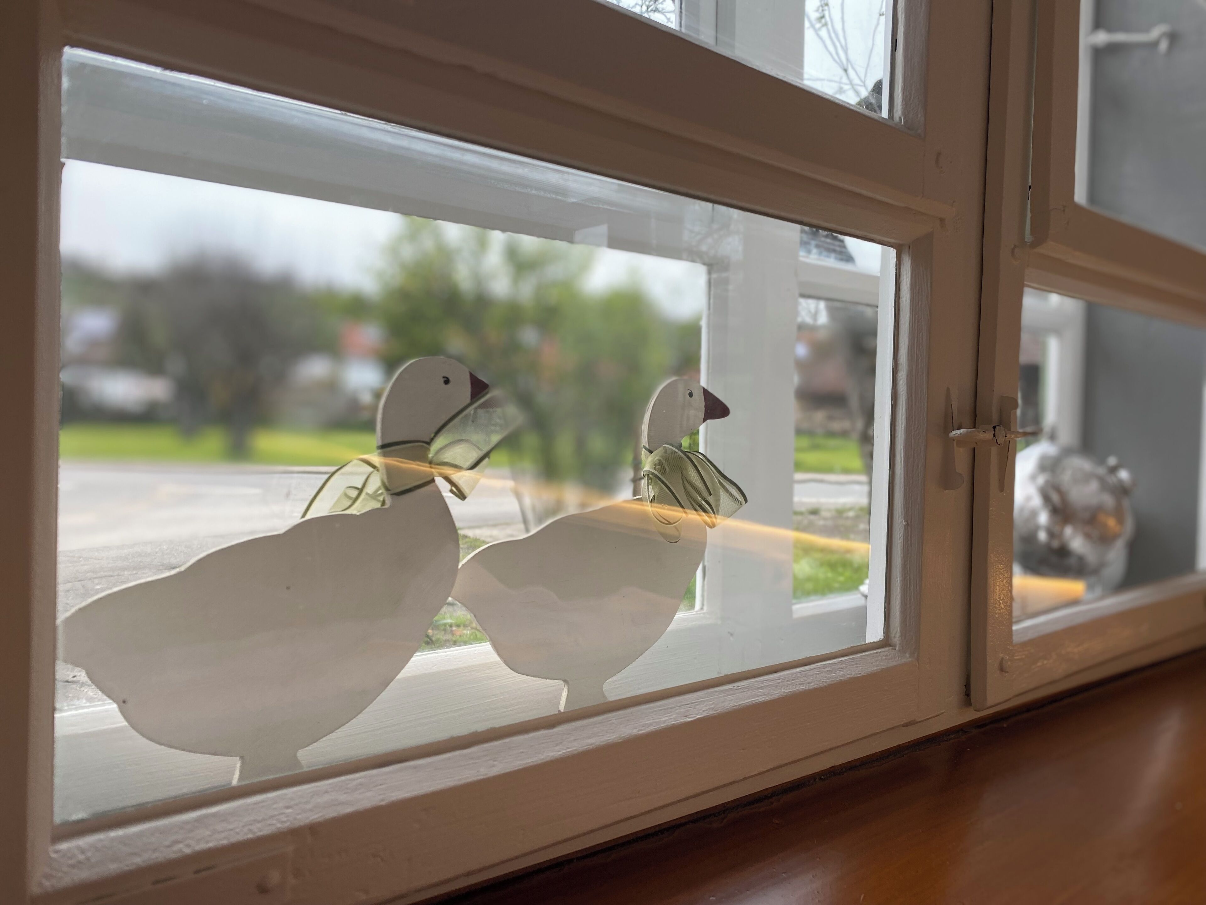 A window with two white bird-shaped decorations.