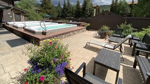 A backyard with a hot tub, patio furniture, and a flower bed.