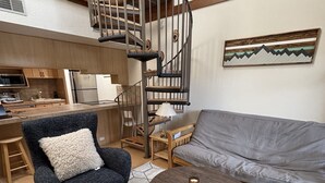 A modern living room with a spiral staircase, a sofa, a chair, and a coffee table.