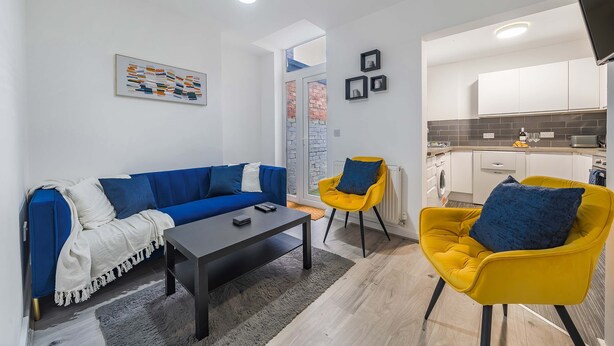 A modern living room with a blue sofa, a yellow armchair, and a coffee table.
