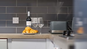 A kitchen counter with a plate of croissants, a bottle of wine, and two glasses.