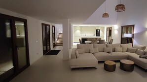 A modern living room with a large L-shaped sectional sofa, a small coffee table, and a dining area in the background.
