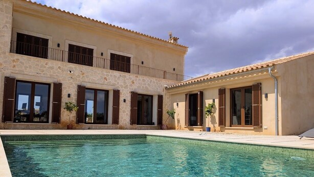 A two-story house with a swimming pool in front.