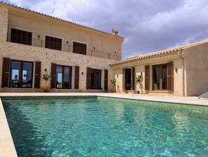 Una casa a due piani con una piscina di fronte.