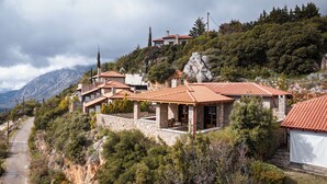 A hillside property with stone buildings, terraced roofs, and a rocky landscape.