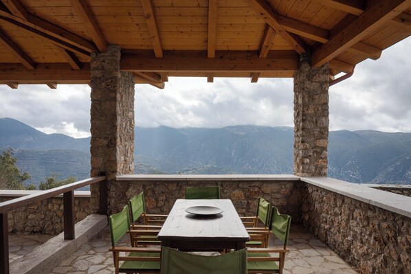 A covered outdoor dining area with stone walls and a table set for four. - Villa Margarita Arachova (Distomo-Arachova-Antikyra)