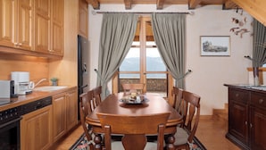 A wooden kitchen with a dining table, chairs, and a view through a window.