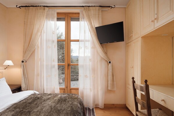 A bedroom with a bed, a TV mounted on the wall, and a window with curtains. - Villa Margarita Arachova (Distomo-Arachova-Antikyra)