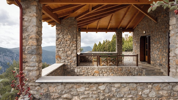 A stone building with a wooden roof and a table and chairs set up outside.