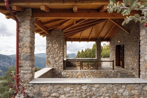 A stone building with a wooden roof and a table and chairs set up outside. - Villa Margarita Arachova (Distomo-Arachova-Antikyra)