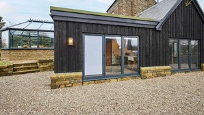A modern building with a dark exterior, large sliding glass doors, and a stone foundation.