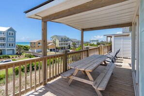 A wooden deck with picnic tables and a covered area overlooking a beach and residential buildings. - Spectacular views from this 2nd Row East side Duplex - New for 2025 Shared Pool (Emerald Isle)