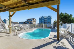 A swimming pool with a wooden deck and white chairs, surrounded by a white fence. - Spectacular views from this 2nd Row East side Duplex - New for 2025 Shared Pool (Emerald Isle)