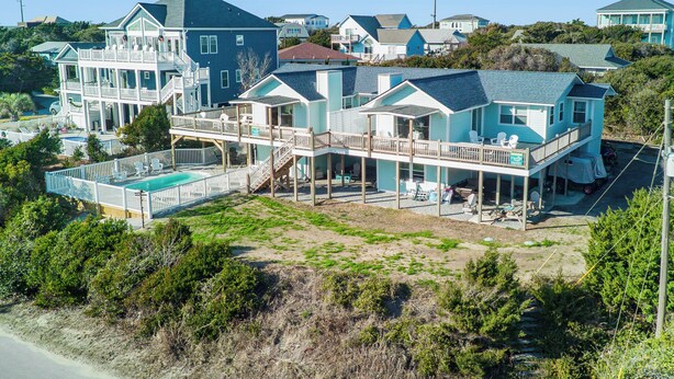 Ein großes, mehrstöckiges Anwesen direkt am Strand mit einem Swimmingpool, mehreren Terrassen und einer überdachten Veranda.