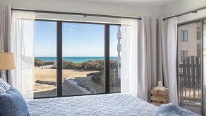 A bedroom with a large sliding glass door leading to a beach view. - Sound of the Sea West 115 - Almost Oceanfront 2 BR 2 BA Condo (Emerald Isle)