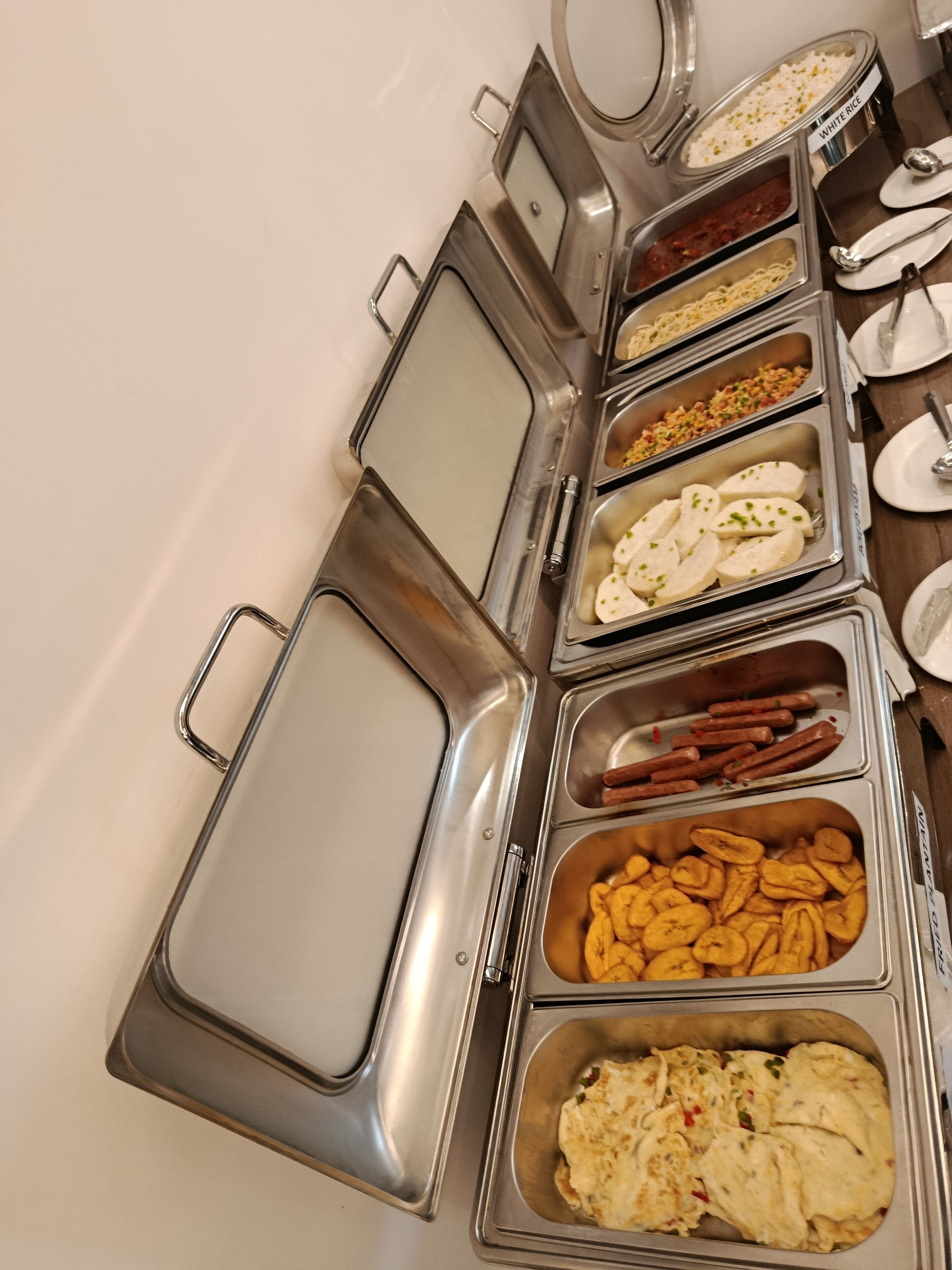A buffet with various food items including white rice, pasta, and different types of appetizers.