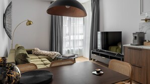 Een moderne woonkamer met een bank, een eettafel, een televisie en een keukenhoek.
