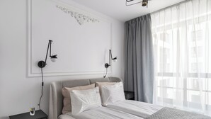 Een moderne slaapkamer met een bed, nachtkastjes en een groot raam met gordijnen.