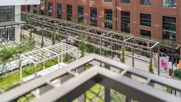 Een modern gebouw met een glazen gevel, een overdekt terras en een bakstenen structuur op de achtergrond.