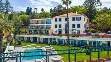 Ein mehrstöckiges Hotel mit Schwimmbad, Außenbereich und üppiger Bepflanzung.