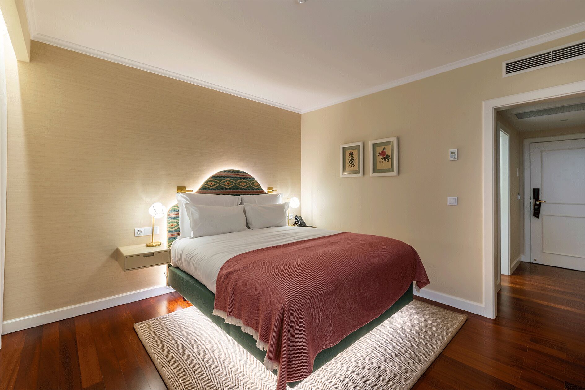 Une chambre à coucher avec un lit, des lampes de chevet, un tapis et une porte.