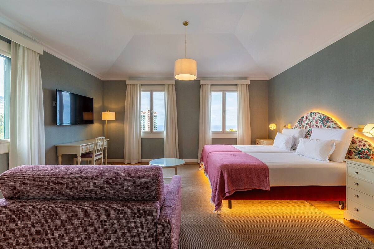 A hotel room with a bed, a desk, a chair, a TV, and a window.