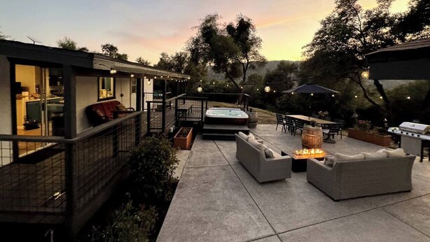 Een terras met buitenmeubilair, een jacuzzi en een barbecue.