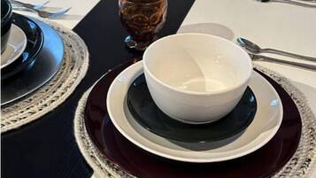 A neatly set dining table with multiple plates, bowls, and glasses.