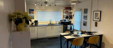 Et kompakt køkken med spiseplads, med en moderne komfur, en vask og en ventilator.