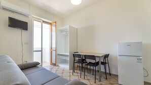 A modern living room with a sofa, a dining table with chairs, a refrigerator, and a TV mounted on the wall. - Sea View Apartment Ac Gallipoli (Gallipoli)