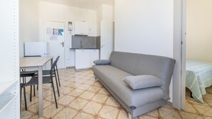 A compact living space with a kitchenette, a sofa, a dining table with chairs, and a bed with a striped bedspread. - Sea View Apartment Ac Gallipoli (Gallipoli)