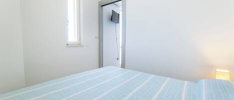 Ein Schlafzimmer mit Bett, Fenster und Tür.