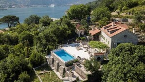 A villa with a swimming pool, surrounded by lush greenery and mountains.