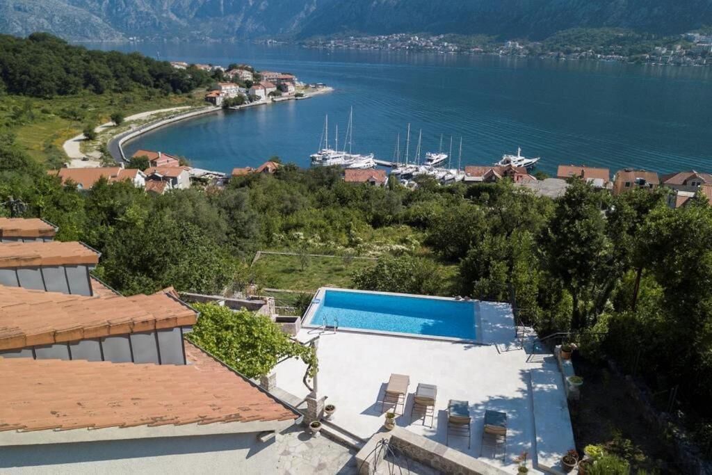 A residential area with a swimming pool, boats, and a mountainous backdrop.