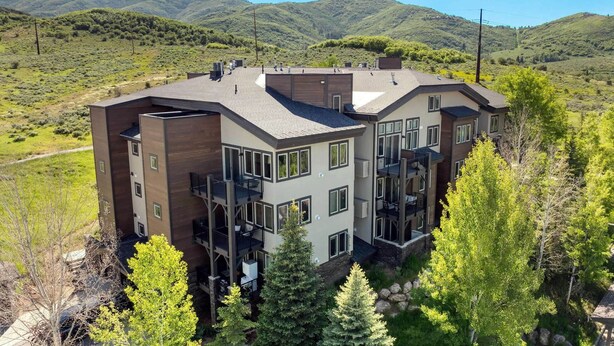 A modern multi-story house with a flat roof, large windows, and a balcony.