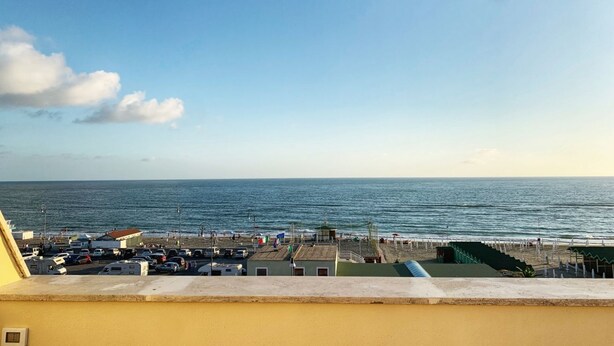 Une vue sur la côte, avec une plage, des véhicules garés et un ciel dégagé.