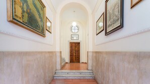 A hallway with marble walls, a wooden door at the end, and framed pictures on the walls. - Villafranca Loft , Modern Studio Nearby the Station (Roma)