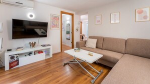A living room with a flat-screen TV, a sofa, a coffee table, and a white entertainment unit. - Villafranca Loft , Modern Studio Nearby the Station (Roma)
