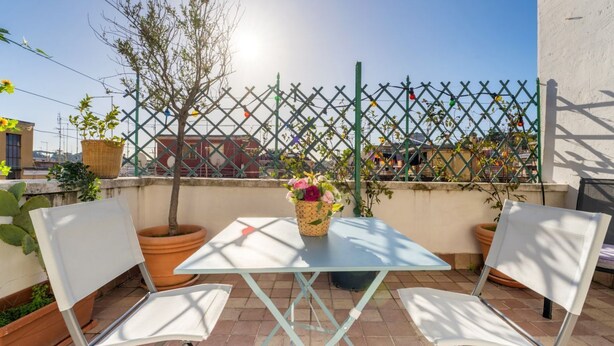 A terrace with a table and two chairs, a potted plant, and a decorative fence. - Welcome Dhome, Cozy penthouse with St. Peter View (Roma)