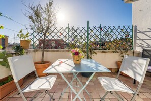 A terrace with a table and two chairs, a potted plant, and a decorative fence. - Welcome Dhome, Cozy penthouse with St. Peter View (Roma)