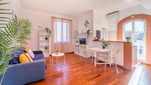 A modern living room with a sofa, a dining table, and a kitchen area. - Welcome Dhome, Cozy penthouse with St. Peter View (Roma)
