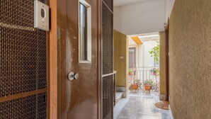 A corridor with a door, a window, and a view of a balcony with potted plants. - Casetta Giolitti, Cozy Apartment in the Heart of Rome (Roma)