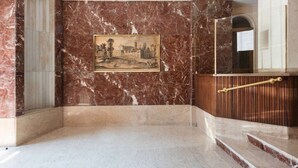 En storslået lobby med en indramet historisk maleri, en træreception og en trappe.