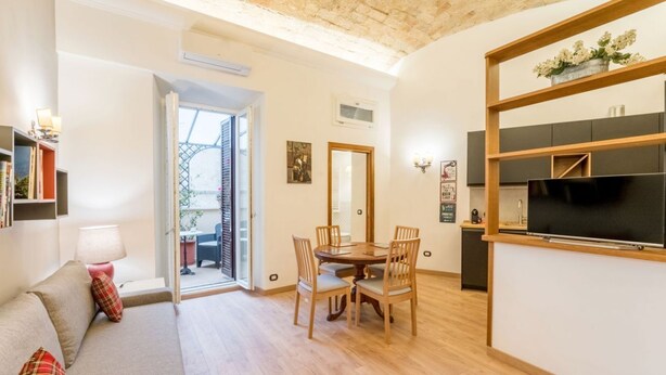 A cozy living room with a sofa, a dining table with chairs, a TV, and a kitchen area. - Atelier dello Statuto, a few steps from Colosseo (Roma)