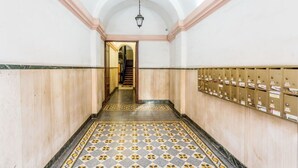 A hallway with a tiled floor, wooden paneling, a staircase, and a row of mailboxes. - Atelier dello Statuto, a few steps from Colosseo (Roma)