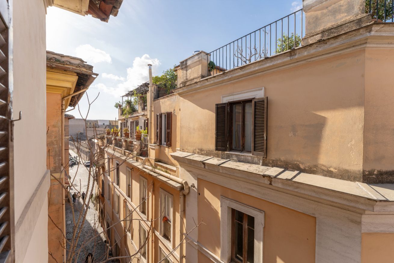A narrow street with buildings featuring balconies and shutters.