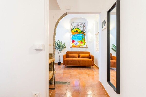 A hallway with a sofa, a stained glass window, and a mirror. - Archetto Loft, Cozy and Cute Space in Trastevere (Roma)